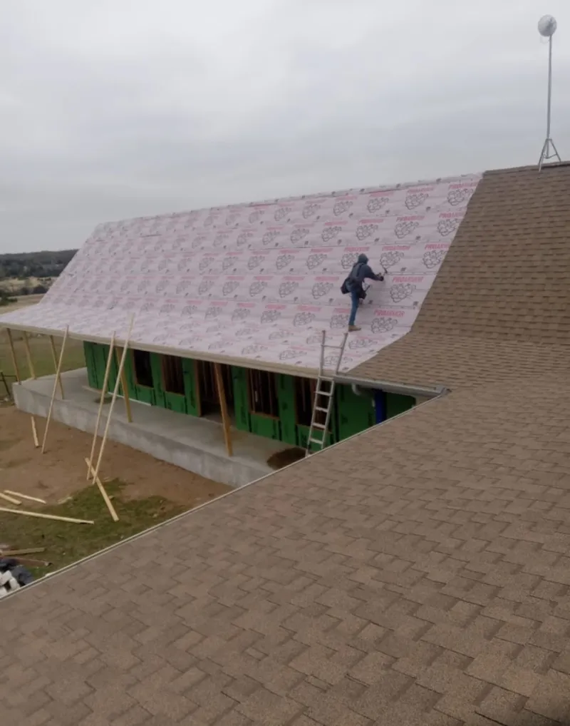 Worker preparing underlayment for a metal roof installation in Sandy
